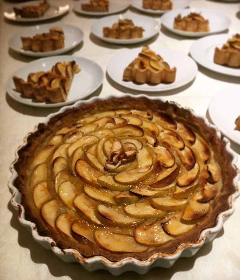 A beautifully arranged apple tart with golden caramelized slices, with individual plated portions ready to be served.